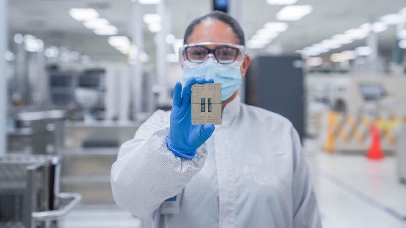 A woman inside and Intel foundry cleanroom holds up a Xeon 6 processor.