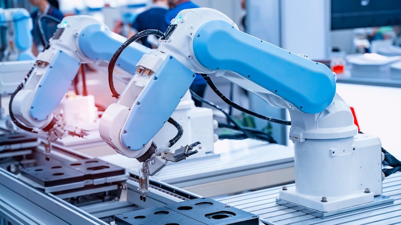 Two robotic arms working on conveyor system.
